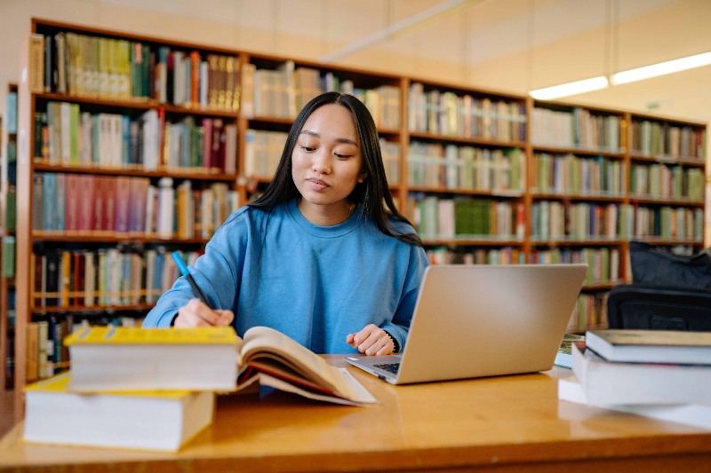 A woman studying in her university's library. 